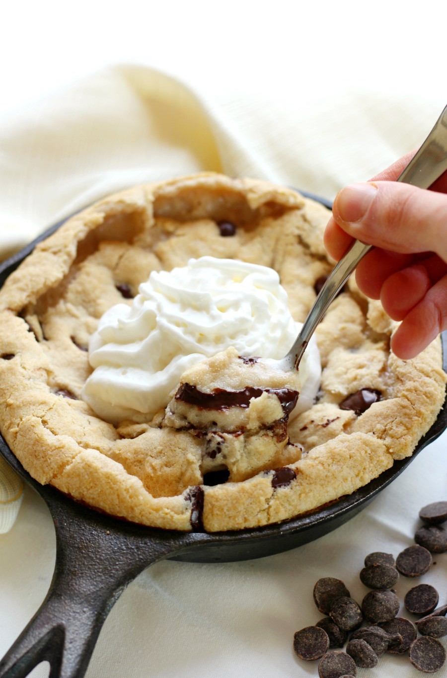 hand-with-spoon-scooping-deep-dish-chocolate-chip-skillet-cookie