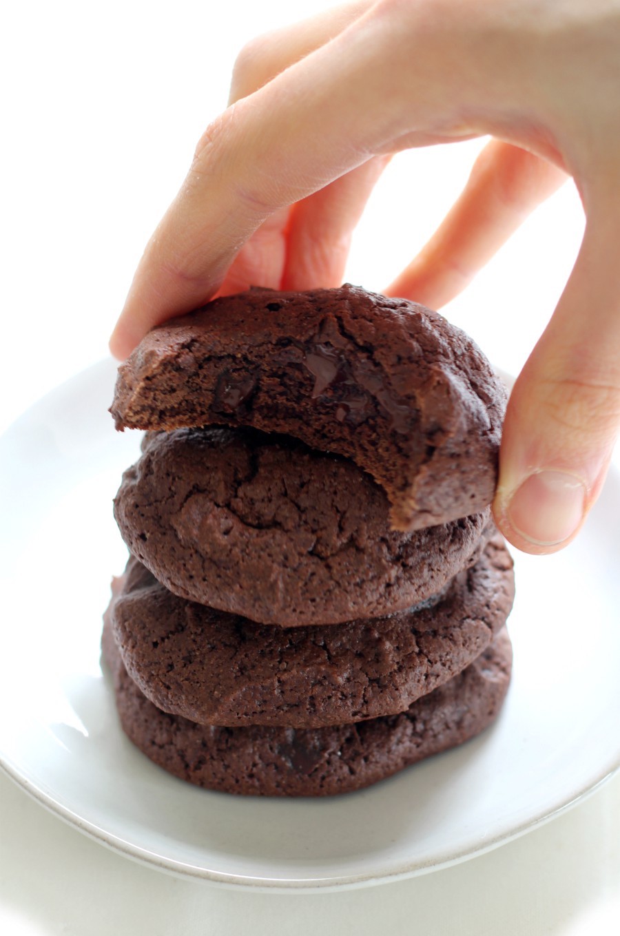 stacked-brownie-cookies-hand-grab-white-plate