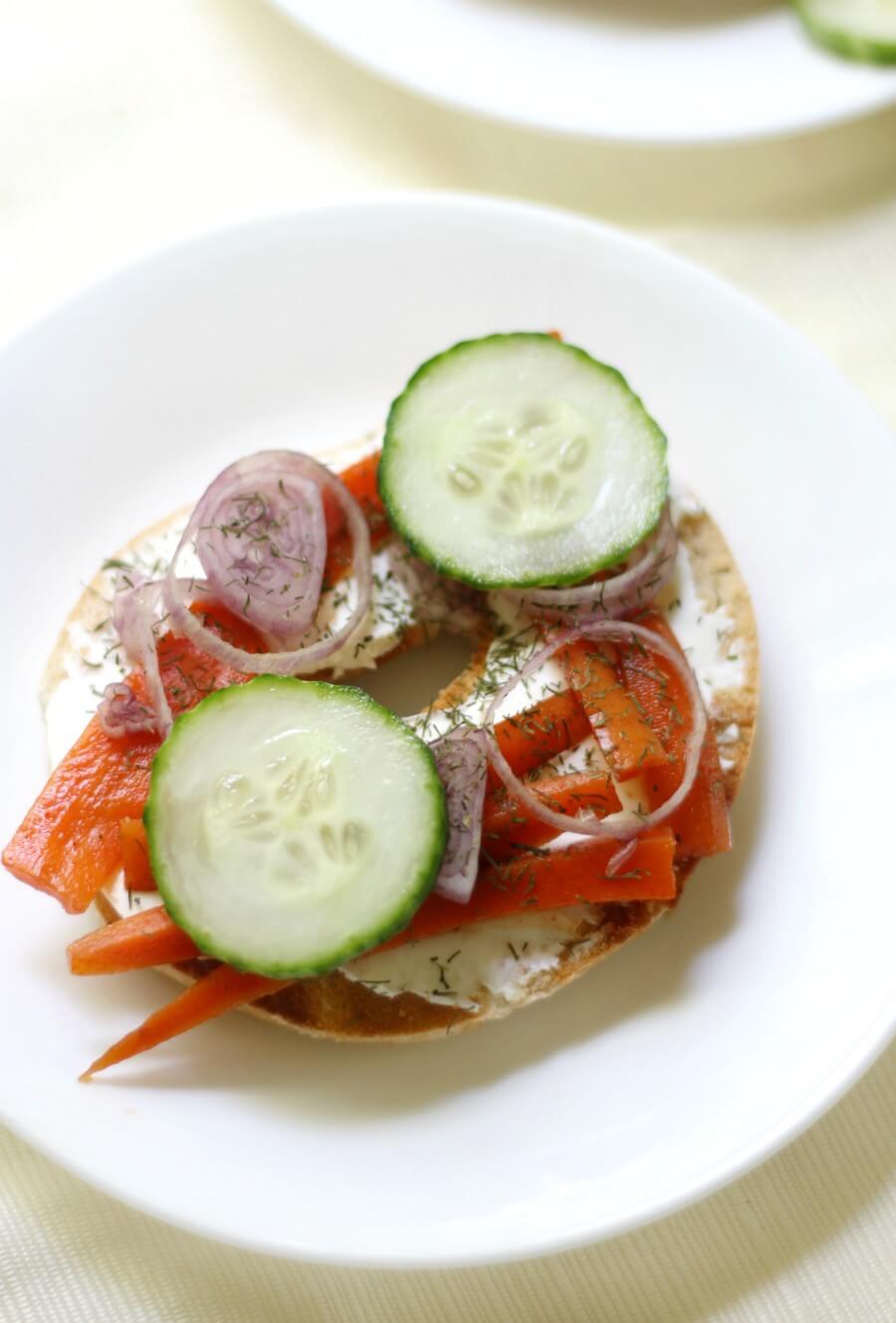 overhead view of opened face gluten-free bagel with vegan carrot lox and toppings