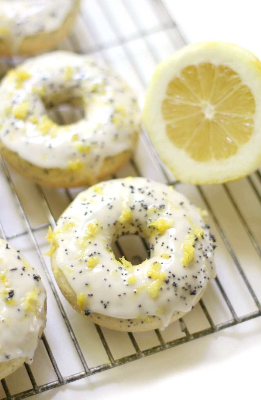 gluten-free lemon poppy seed doughnuts on a wire rack with a lemon