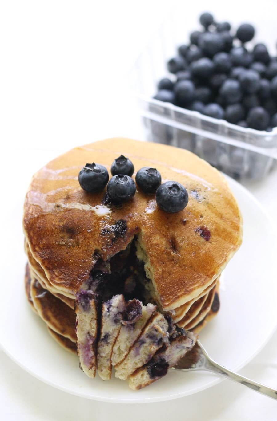 fork with gluten-free blueberry pancakes on white plate
