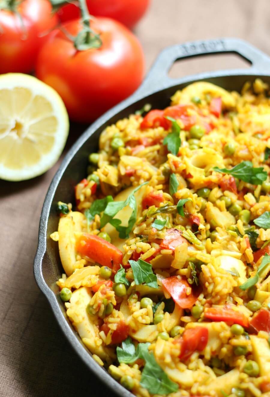 spanish vegan paella with tomatoes and lemons in background