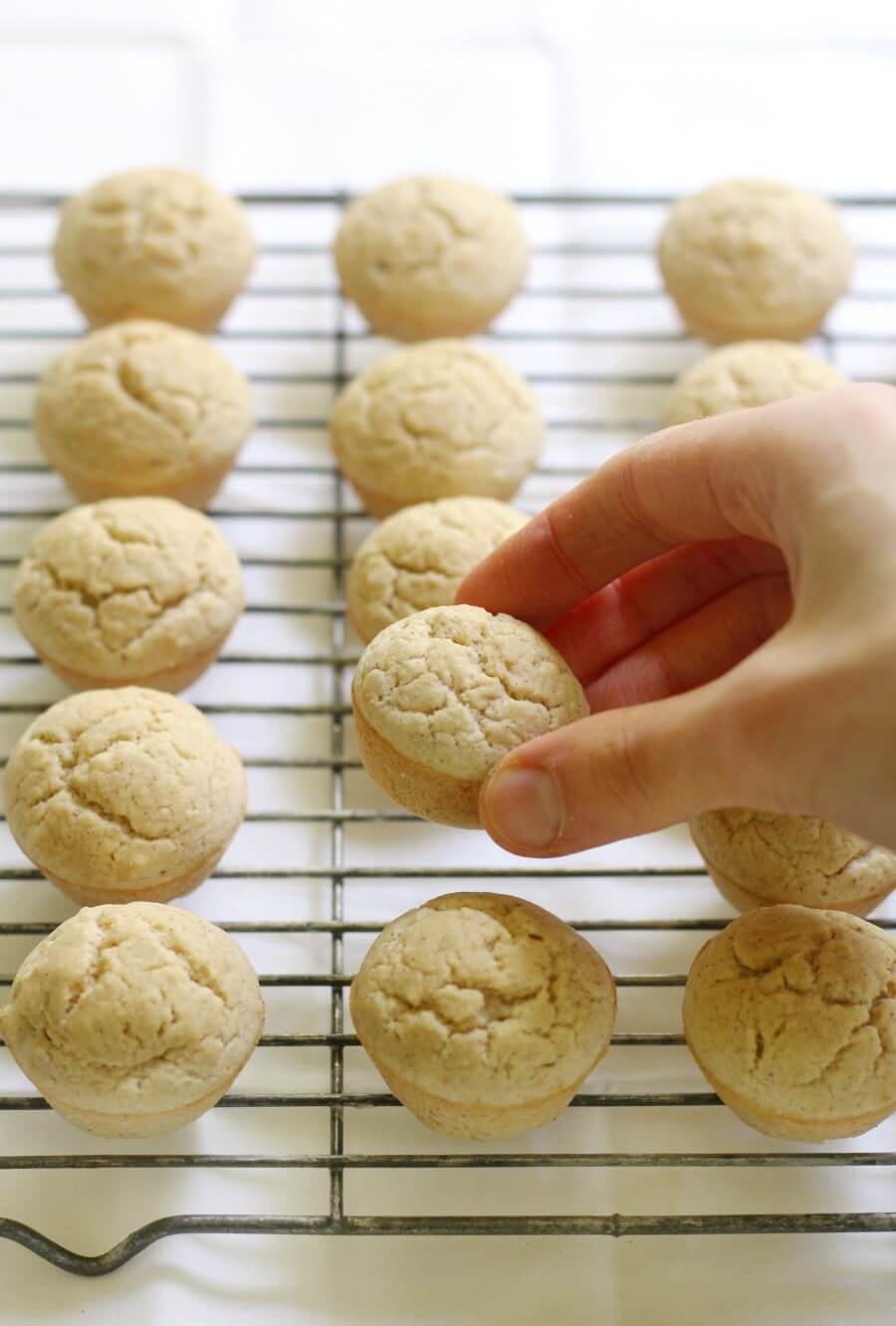 hand grabbing a mini applesauce muffin off a wire cooling rack