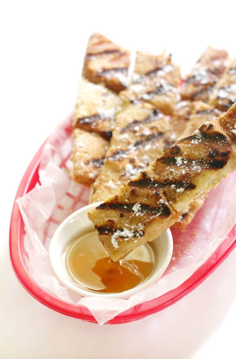 gluten-free grilled french toast skewer being dipped in maple syrup