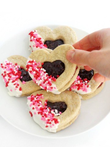 hand grabbing a gluten-free valentine's day heart cookie from plate