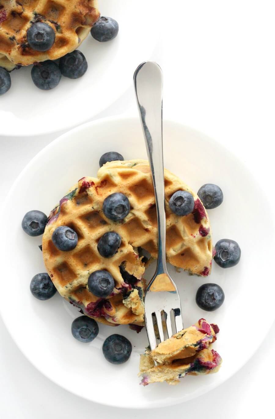 overhead view of two plates of gluten-free blueberry waffles