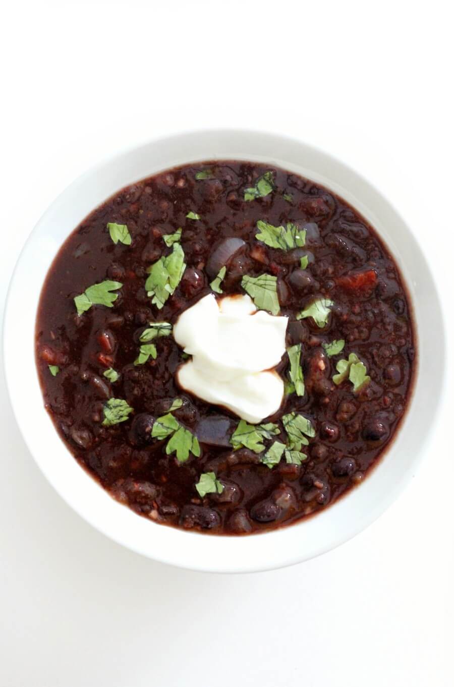 centered overhead view of spicy chipotle black bean soup with spoon in white bowl