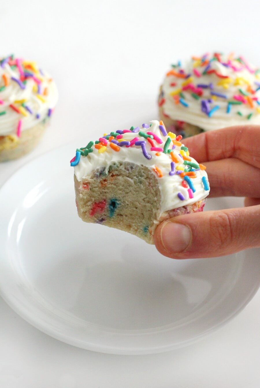 hand holding a gluten-free funfetti cupcake above plate