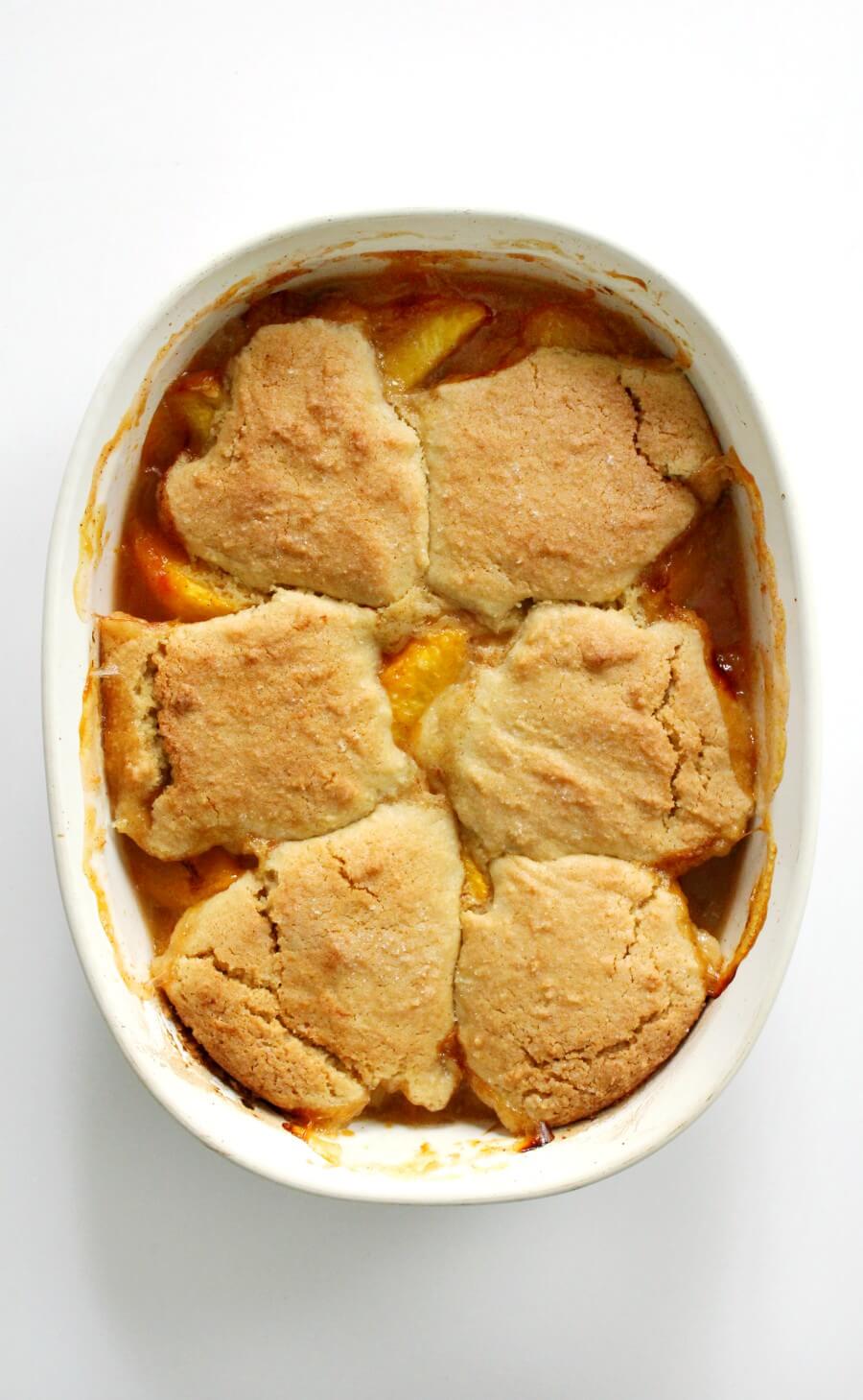 overhead view of finished gluten-free peach cobbler in white casserole dish