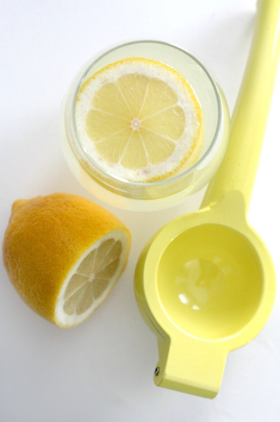 glass of healthy lemonade with lemon and juicer