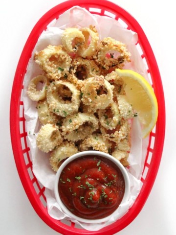 overhead view of vegan calamari with lemon and cocktail sauce in red basket