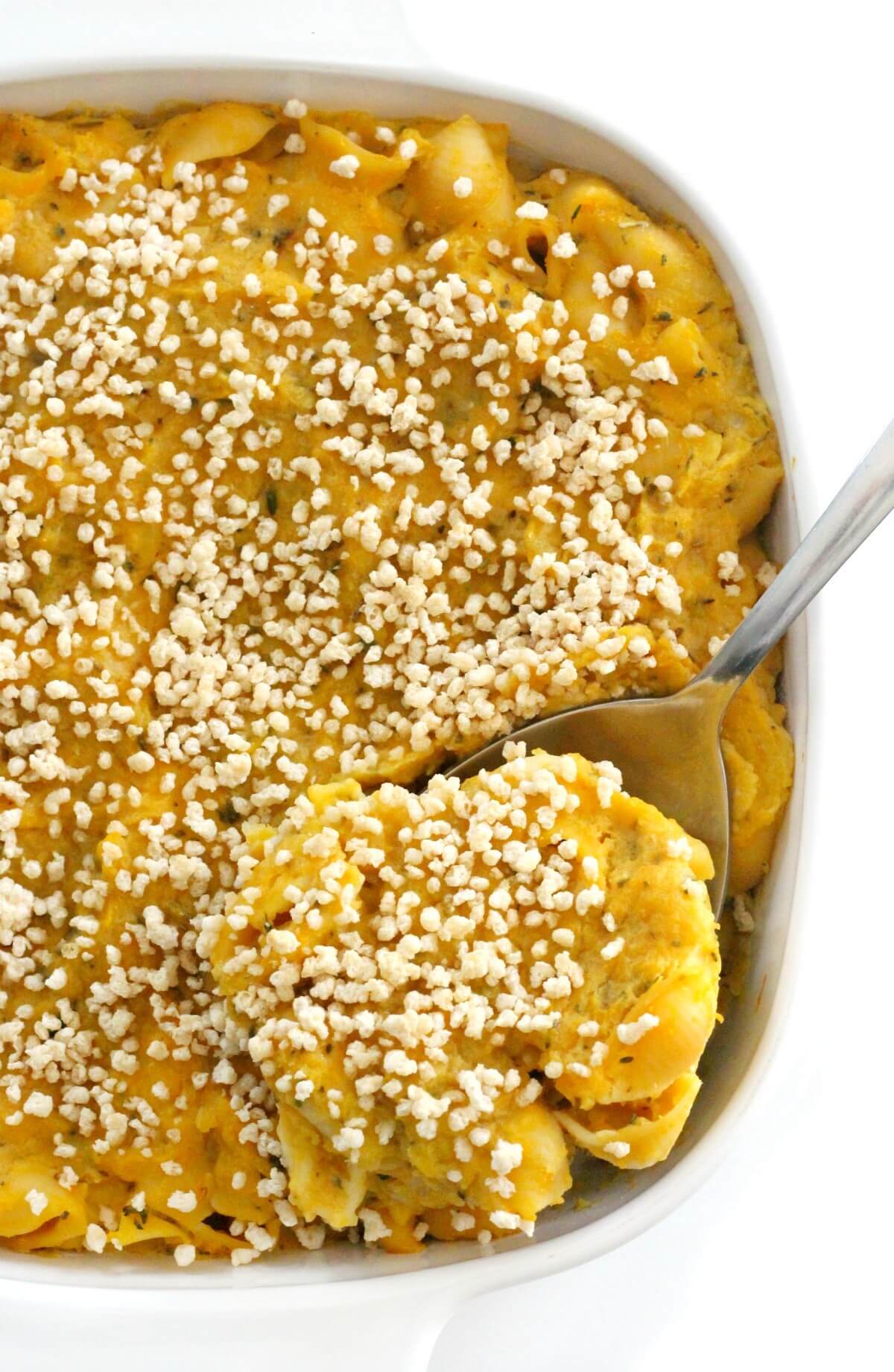 metal spoon scooping out baked vegan butternut squash mac and cheese from casserole dish
