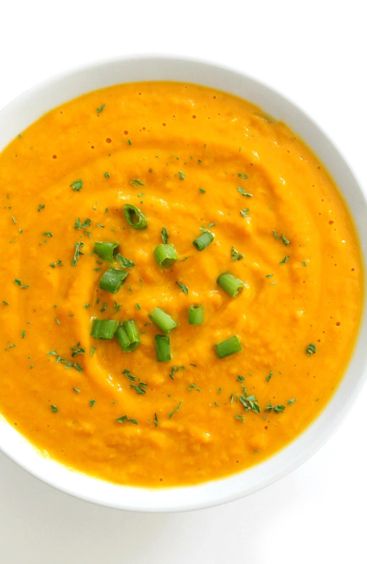 white bowl of vegan curried pumpkin soup with parsley