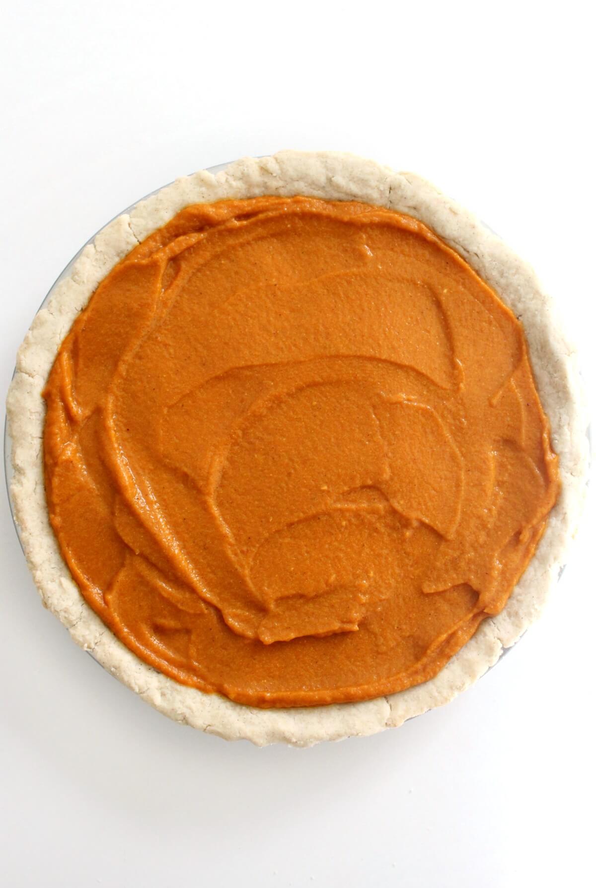 vegan pumpkin pie filling poured into unbaked pie shell