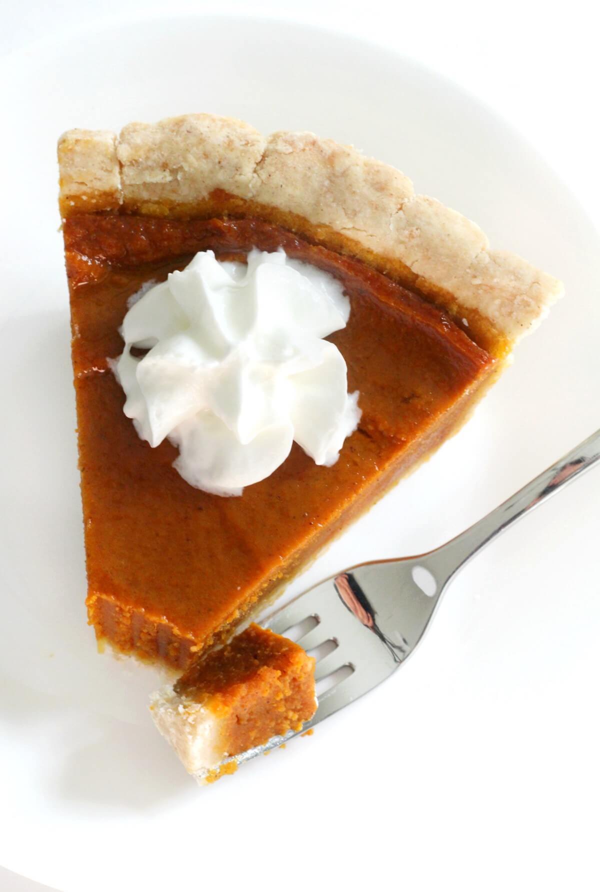 overhead view of cut slice of gluten-free vegan pumpkin pie with whipped cream