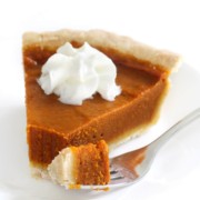 forkful and slice of gluten-free vegan pumpkin pie on plate with whipped cream