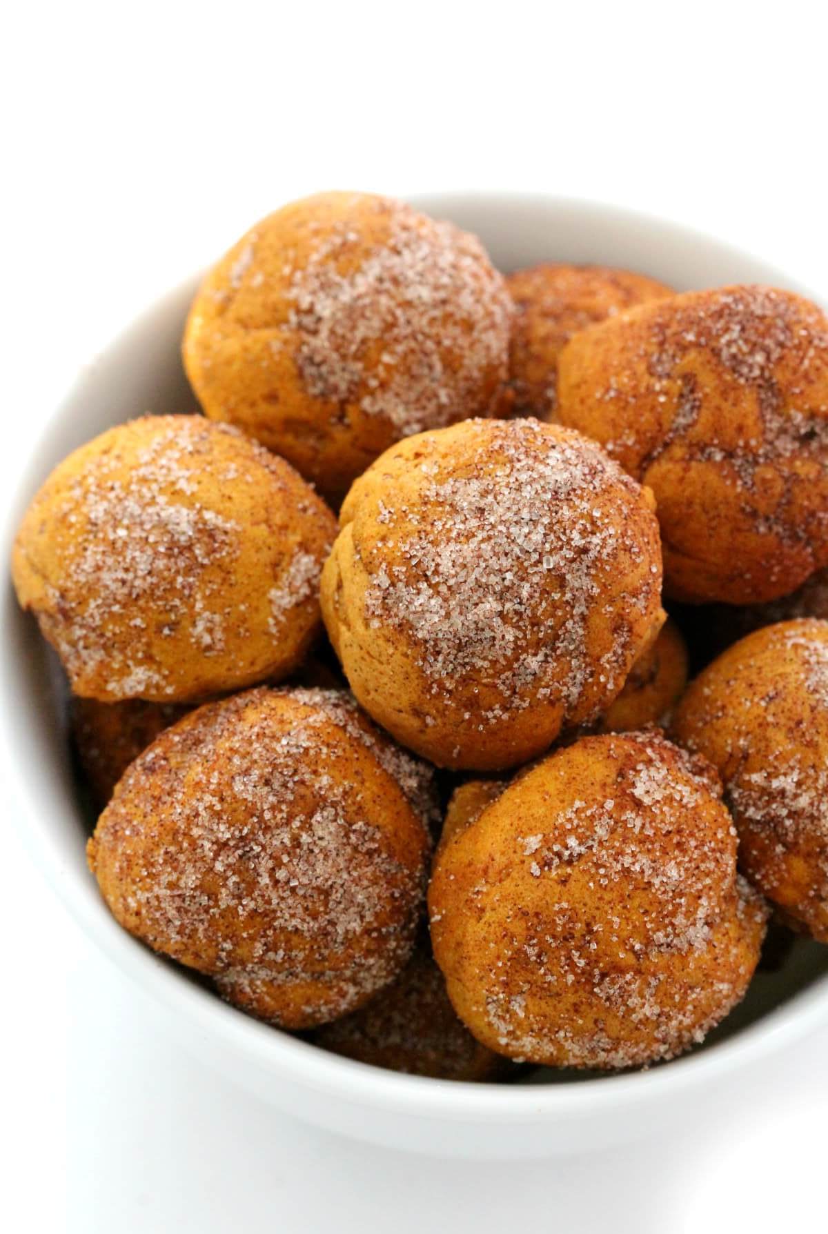 close-up of cinnamon sugar coated pumpkin donut holes in white bowl