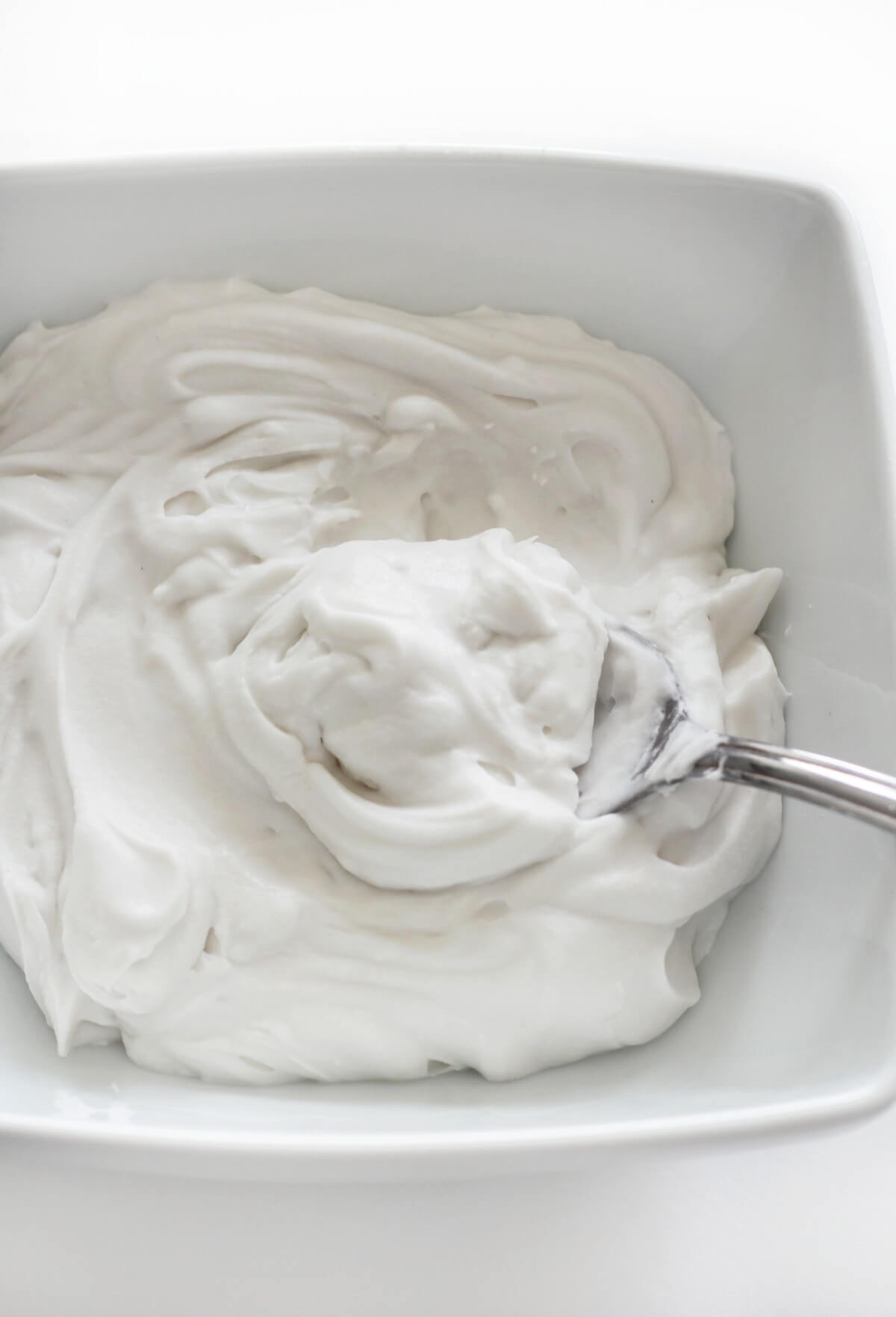 coconut whipped cream in bowl with spoon scoop