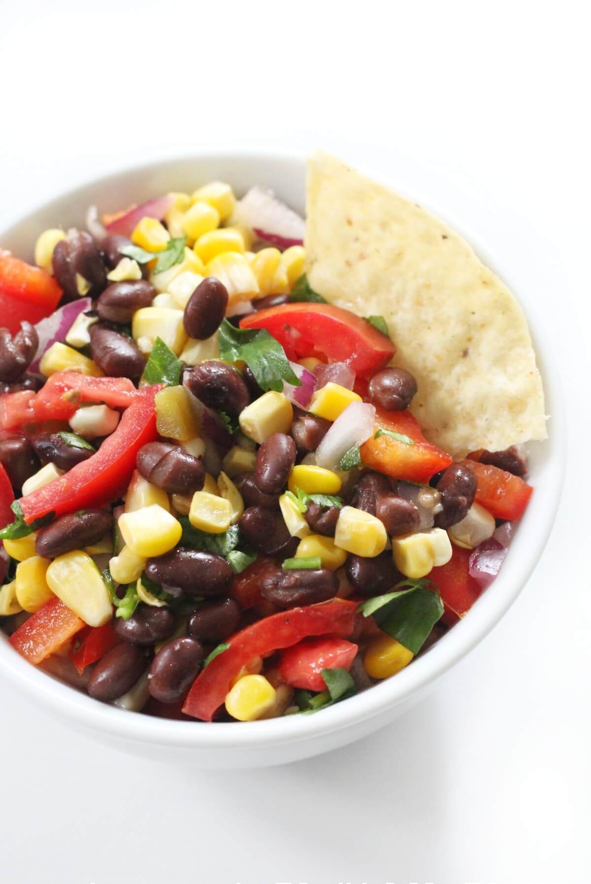 small serving bowl with black bean corn salsa and chip