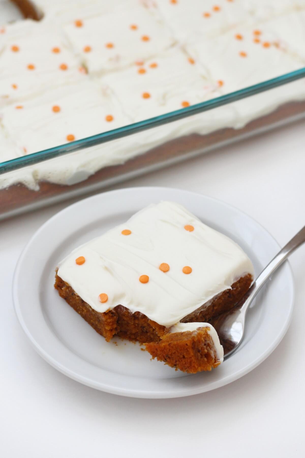 vegan pumpkin cake in glass pan with slice of pumpkin cake on white plate
