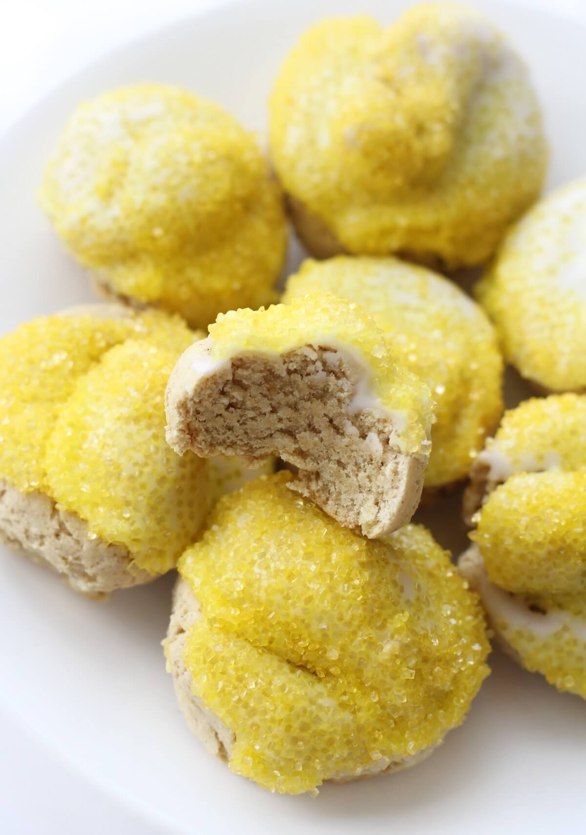 plate of iced gluten-free Italian lemon cookies with one bitten into
