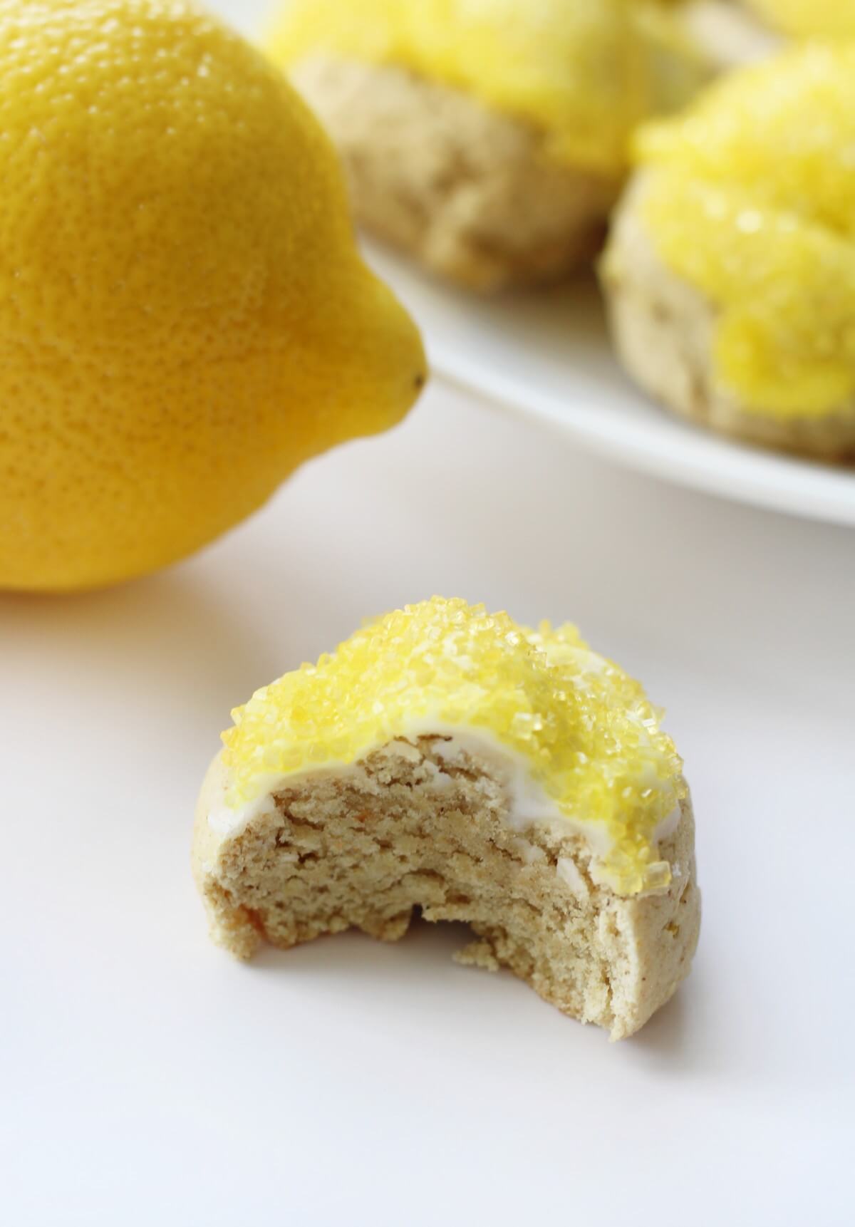 bitten into gluten-free lemon knot cookie with glaze and lemon in background