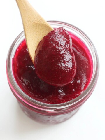 spoon scooping out jellied cranberry sauce from jar