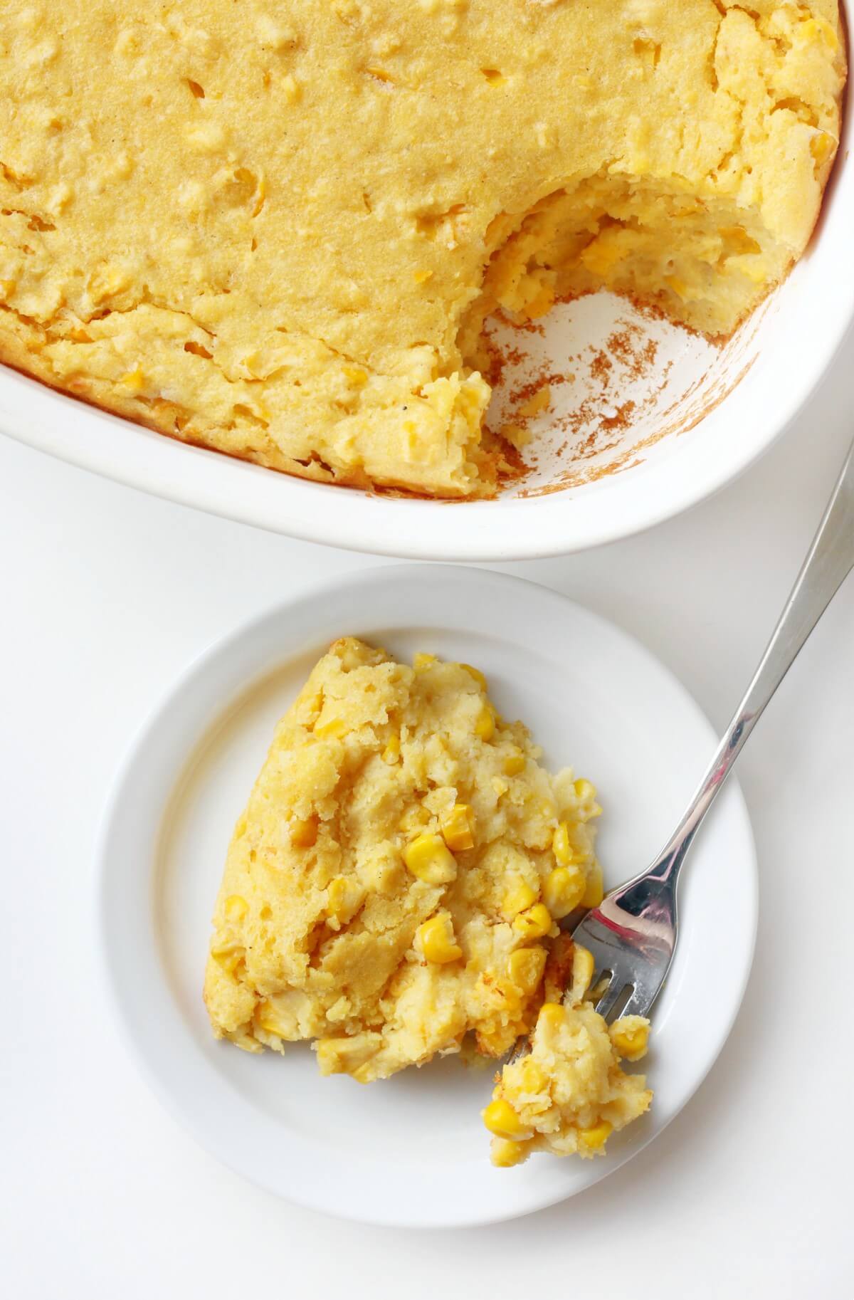 scooped out vegan corn casserole and serving on plate with fork bite