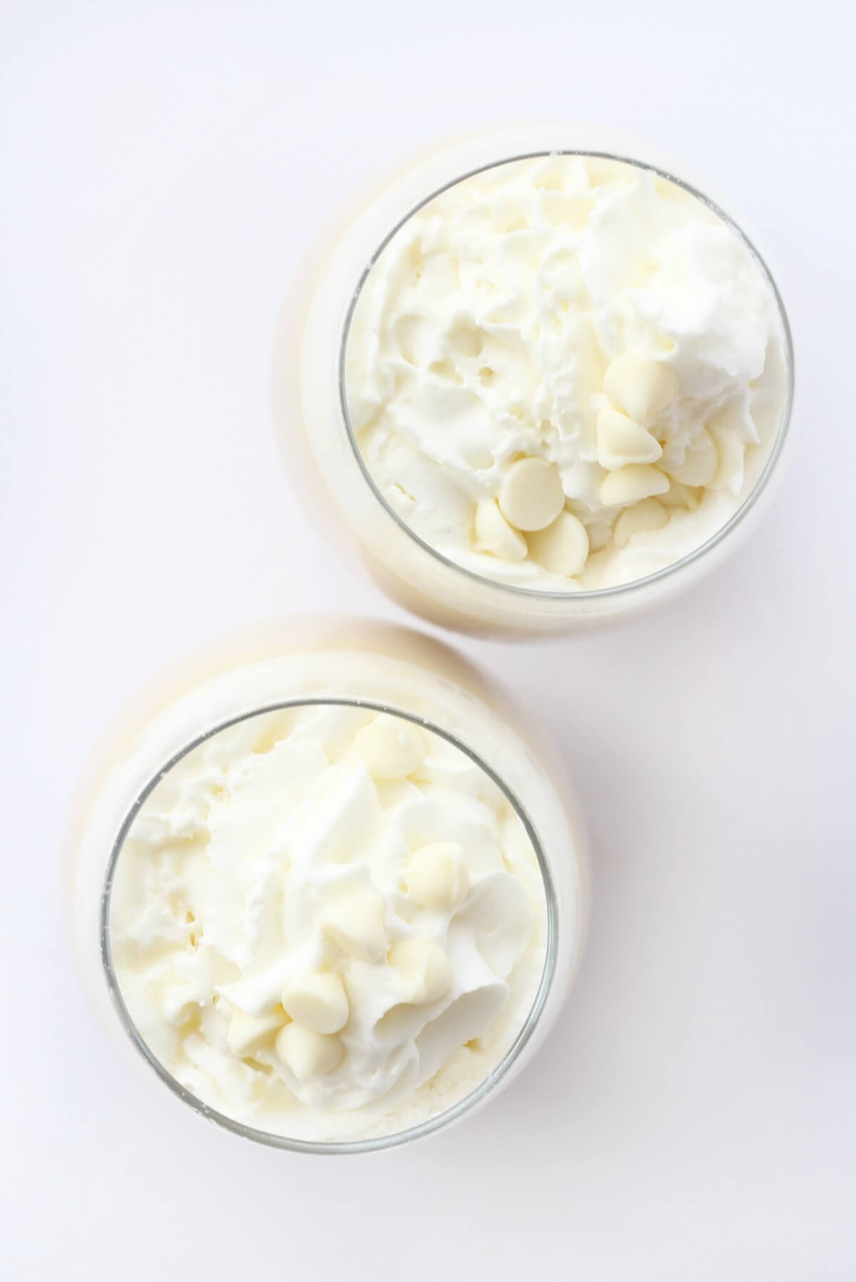 overhead view of two glasses with vegan white hot chocolate and whipped cream