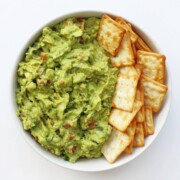 overhead view of bowl with fresh authentic guacamole and crackers