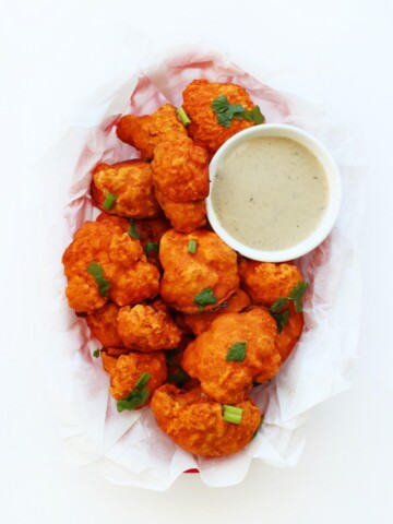 overhead view of vegan buffalo cauliflower in red basket with ranch