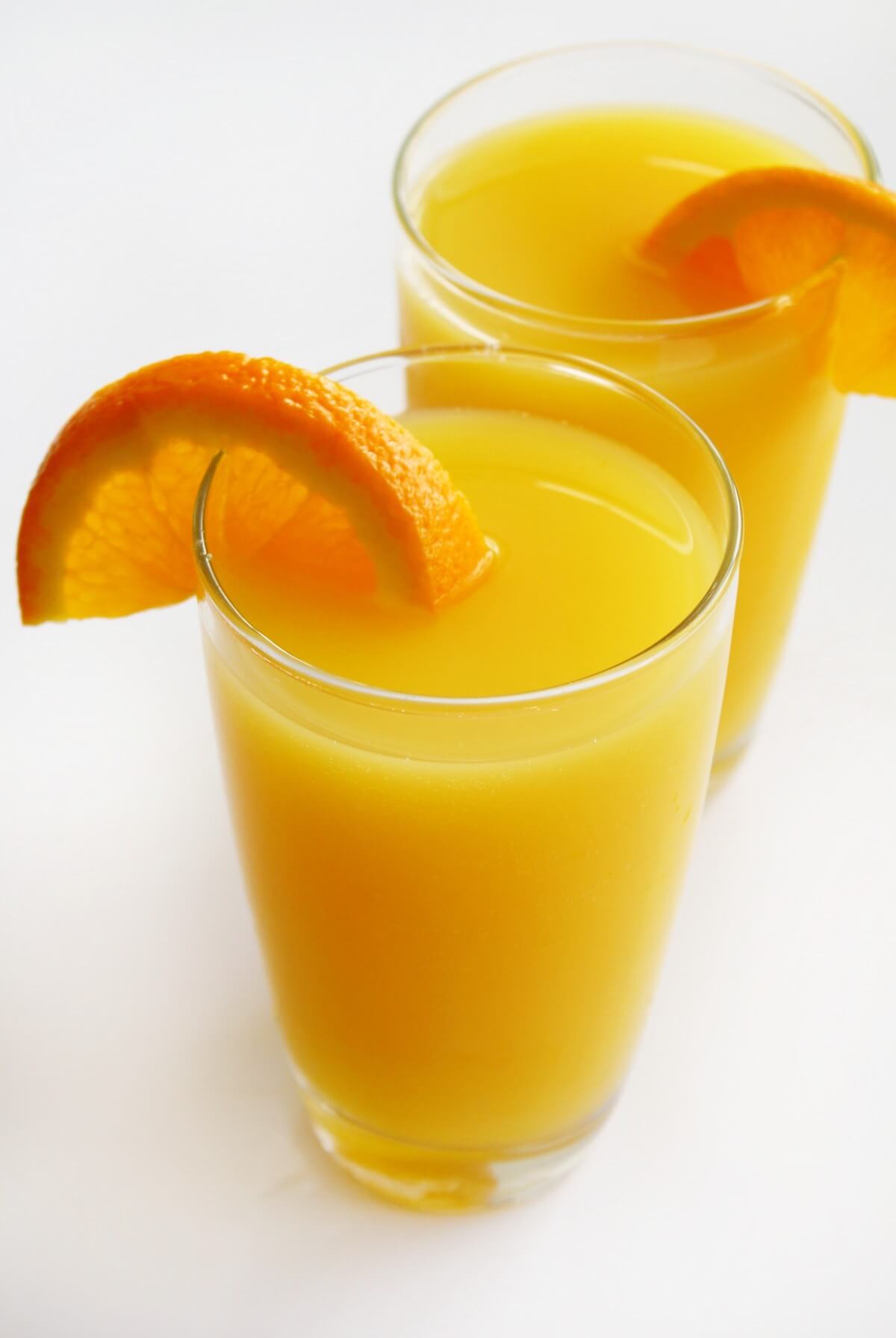 tall glass with non-alcoholic mimosa and orange slice