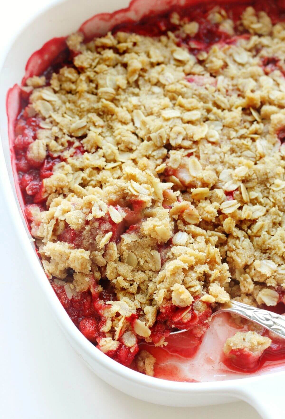 scooping gluten-free strawberry crisp out of casserole dish