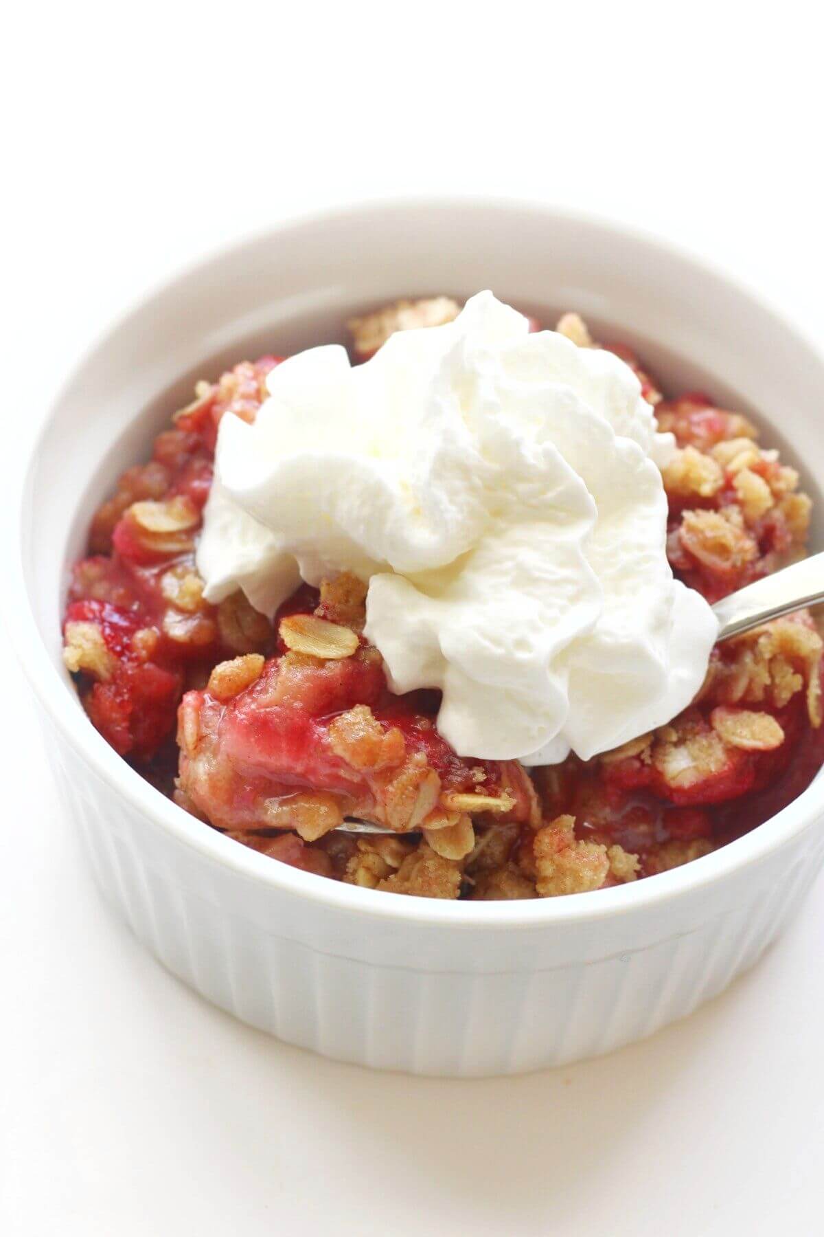 close up of scoop of strawberry crisp with whipped cream