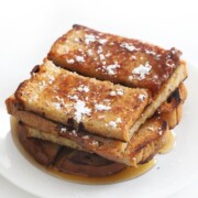 plated tower of gluten-free vegan cinnamon french toast stocks with syrup and powdered sugar