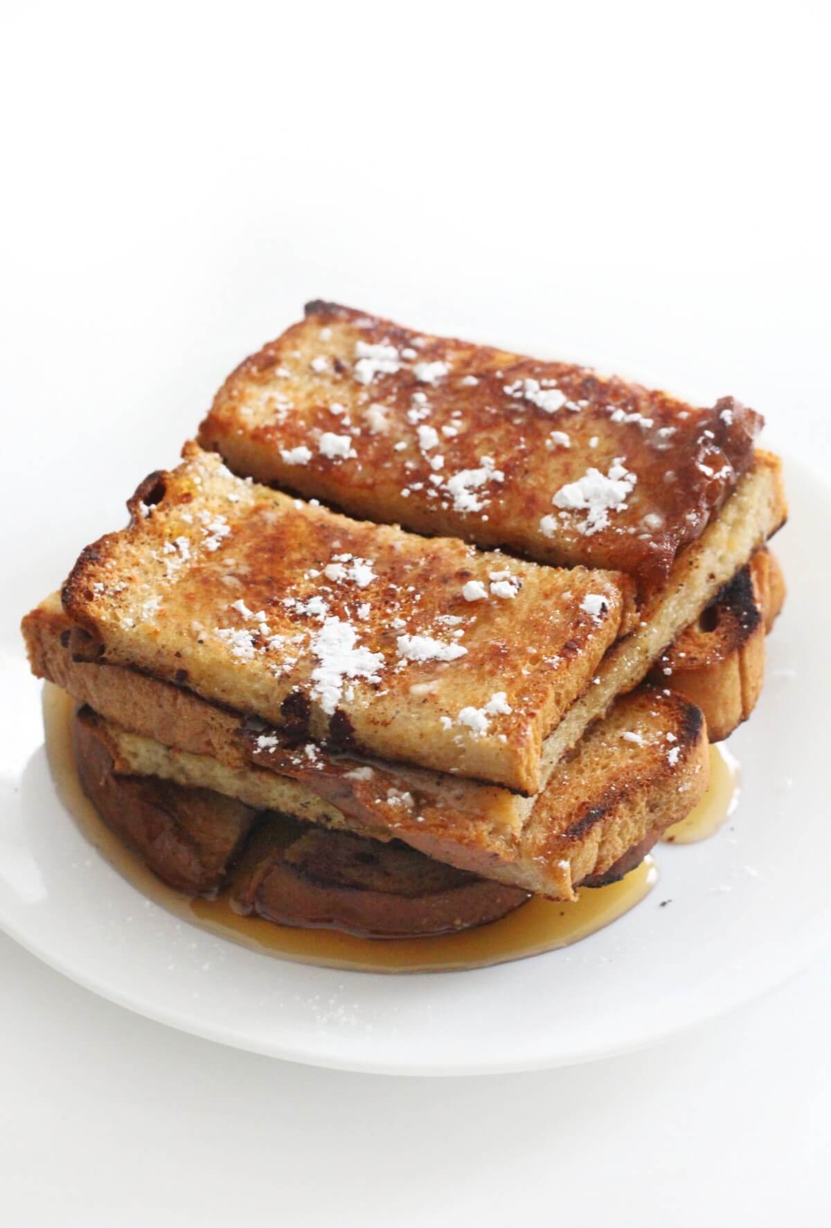 plated tower of gluten-free vegan cinnamon french toast stocks with syrup and powdered sugar