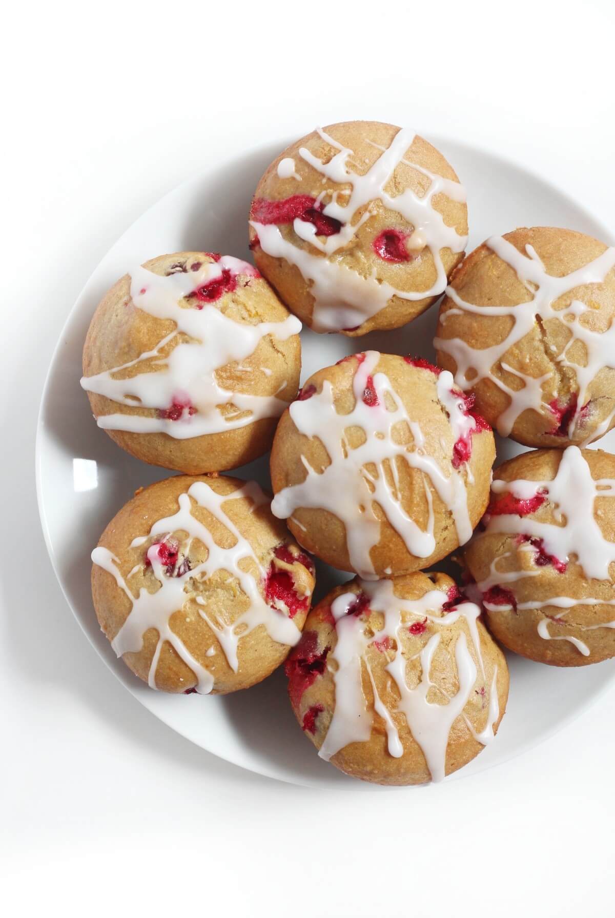 overhead left side view of gluten-free cranberry orange muffins with glaze on plate
