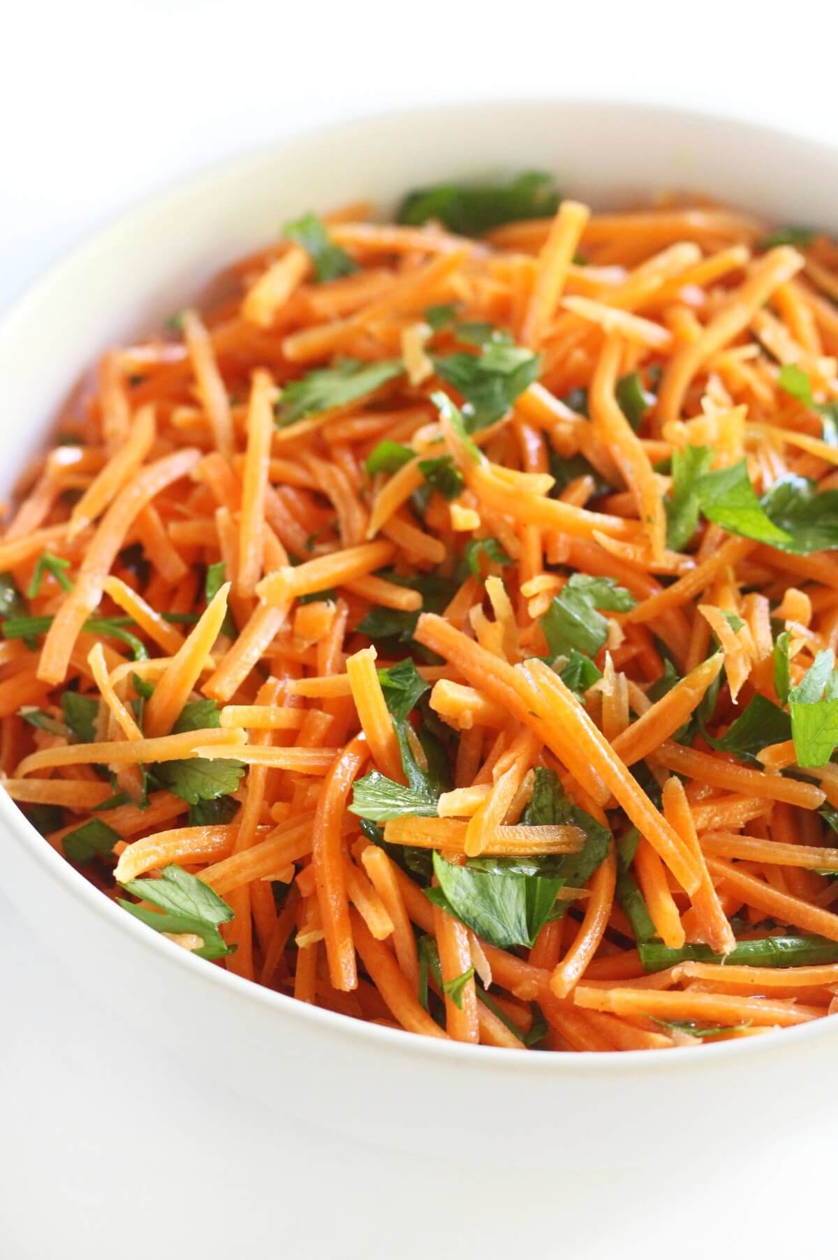 close up side view of French carrot salad in white bowl