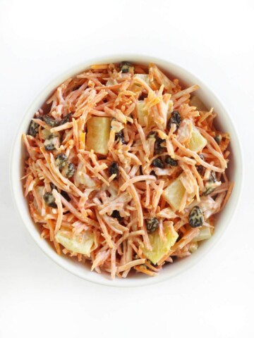 overhead view of vegan carrot raisin salad in white serving bowl
