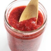 wooden spoon scooping fresh strawberry chia jam from jar
