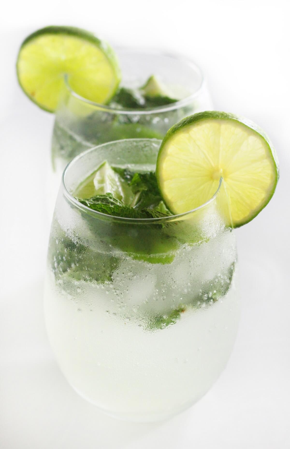 two virgin mojitos with lime slices on rim