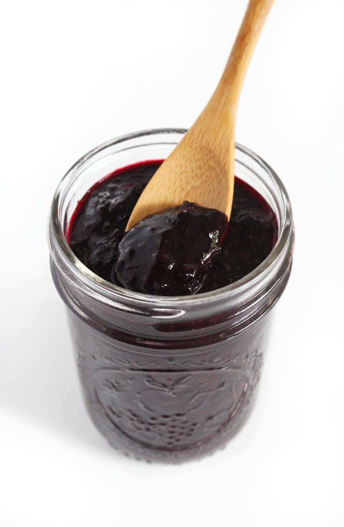 glass jar of blueberry chia jam and wooden spoon