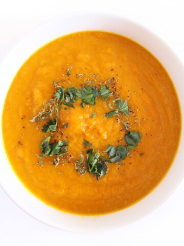 overhead view of vegan carrot ginger soup with cilantro in white bowl