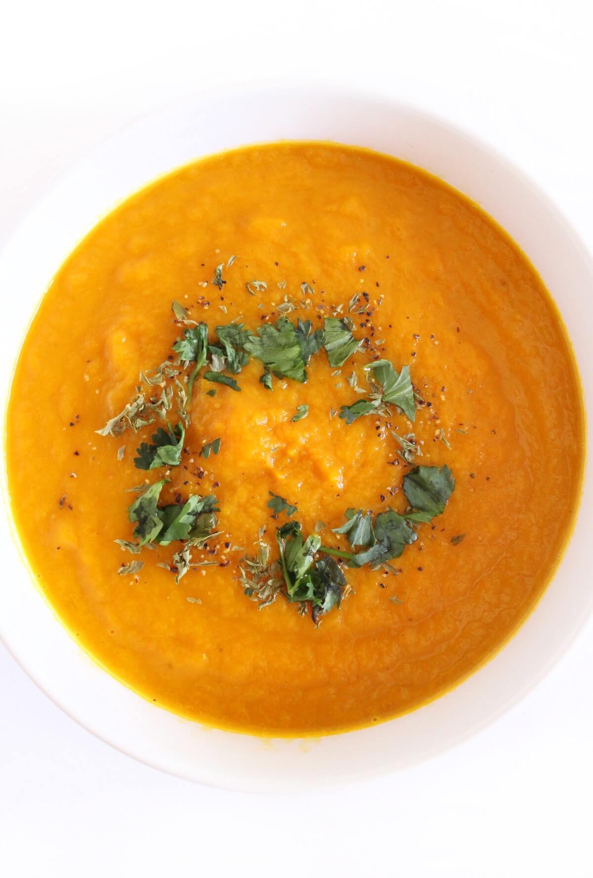 overhead view of vegan carrot ginger soup with cilantro in white bowl