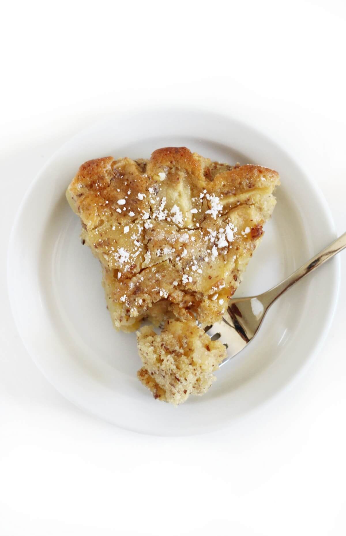 overhead view of french apple cake slice with forkful on plate