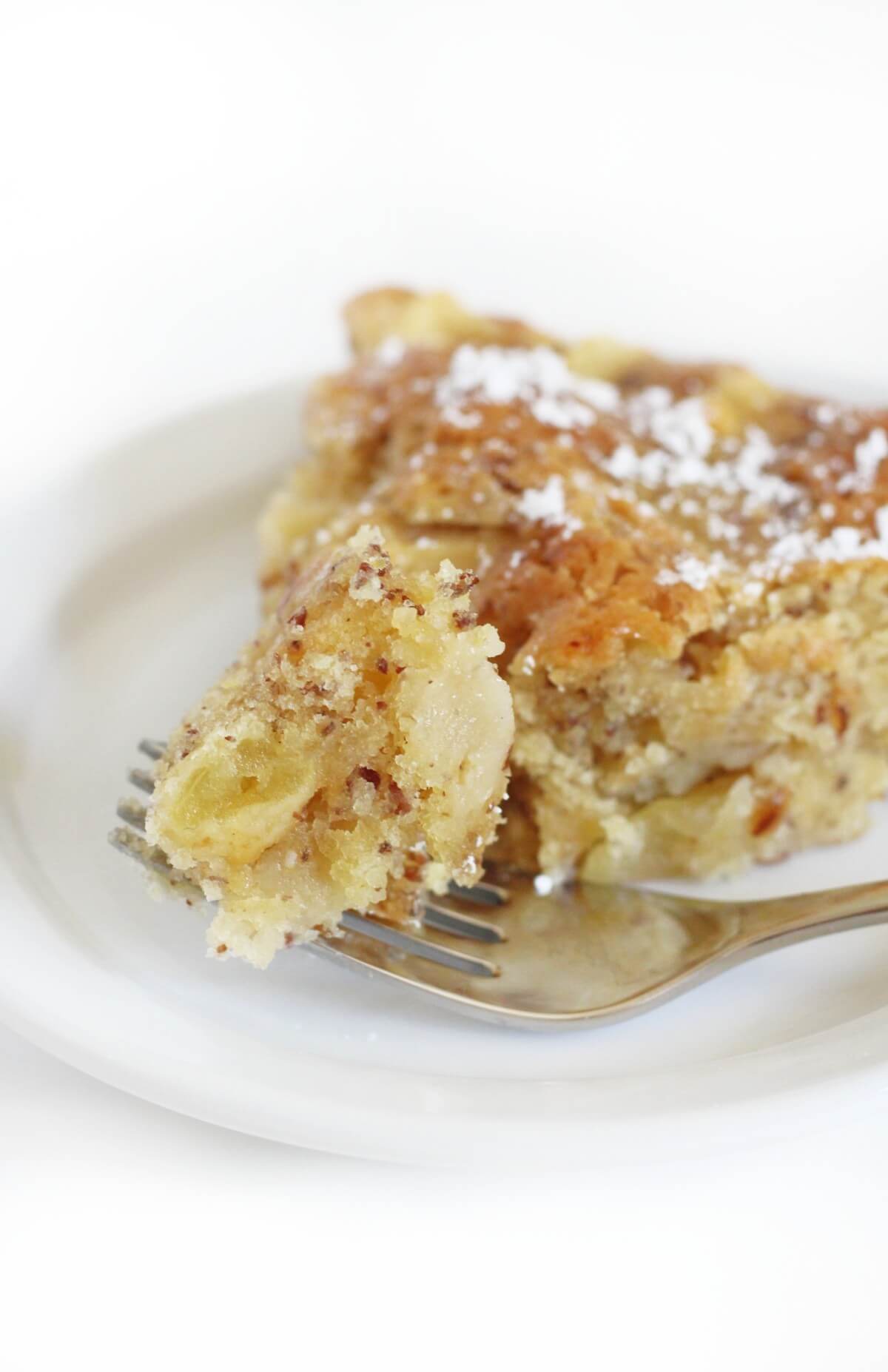 close up of forkful bite of gluten-free french apple cake with powdered sugar