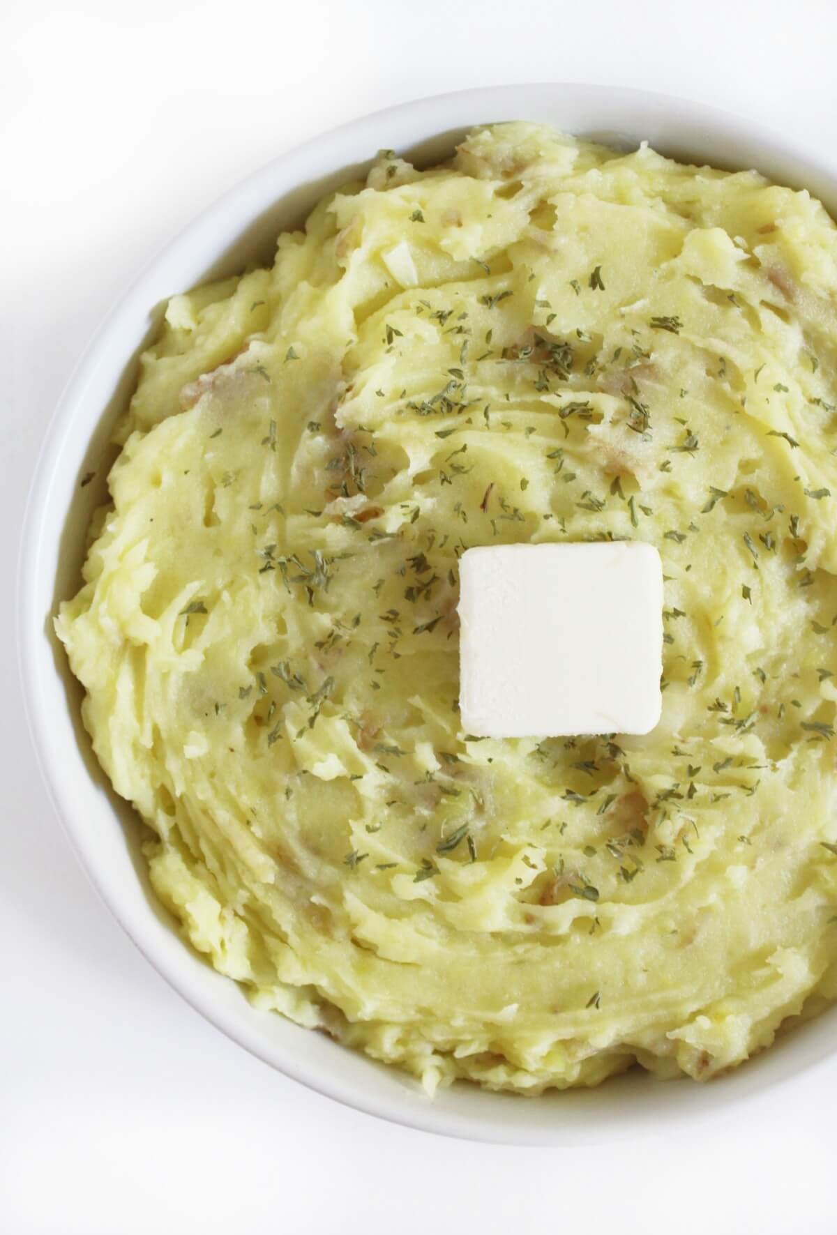 serving bowl with creamy vegan garlic mashed potatoes and extra butter.