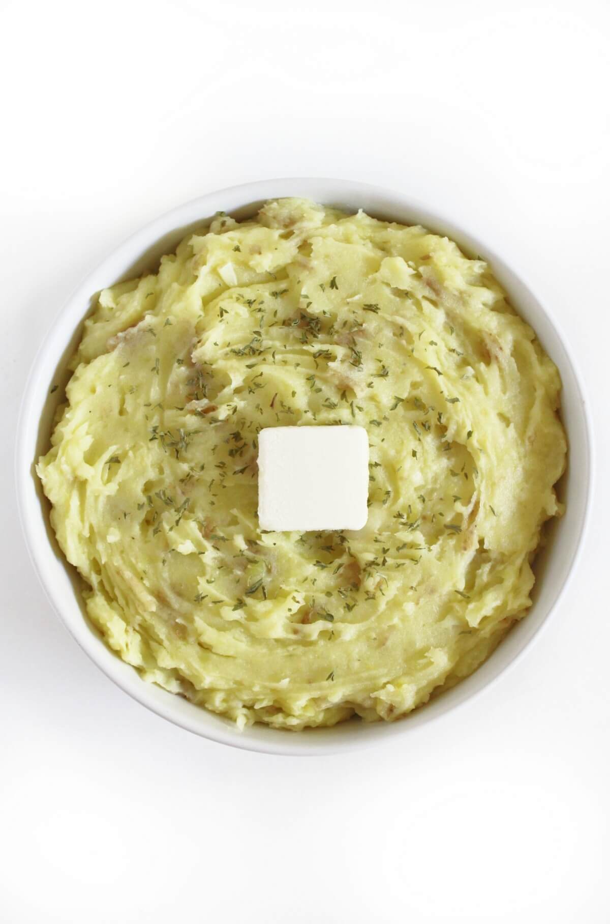 creamy vegan garlic mashed potatoes in serving bowl with butter.