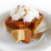 forkful bite of gluten-free vegan pumpkin pie bar with whipped cream and cinnamon.