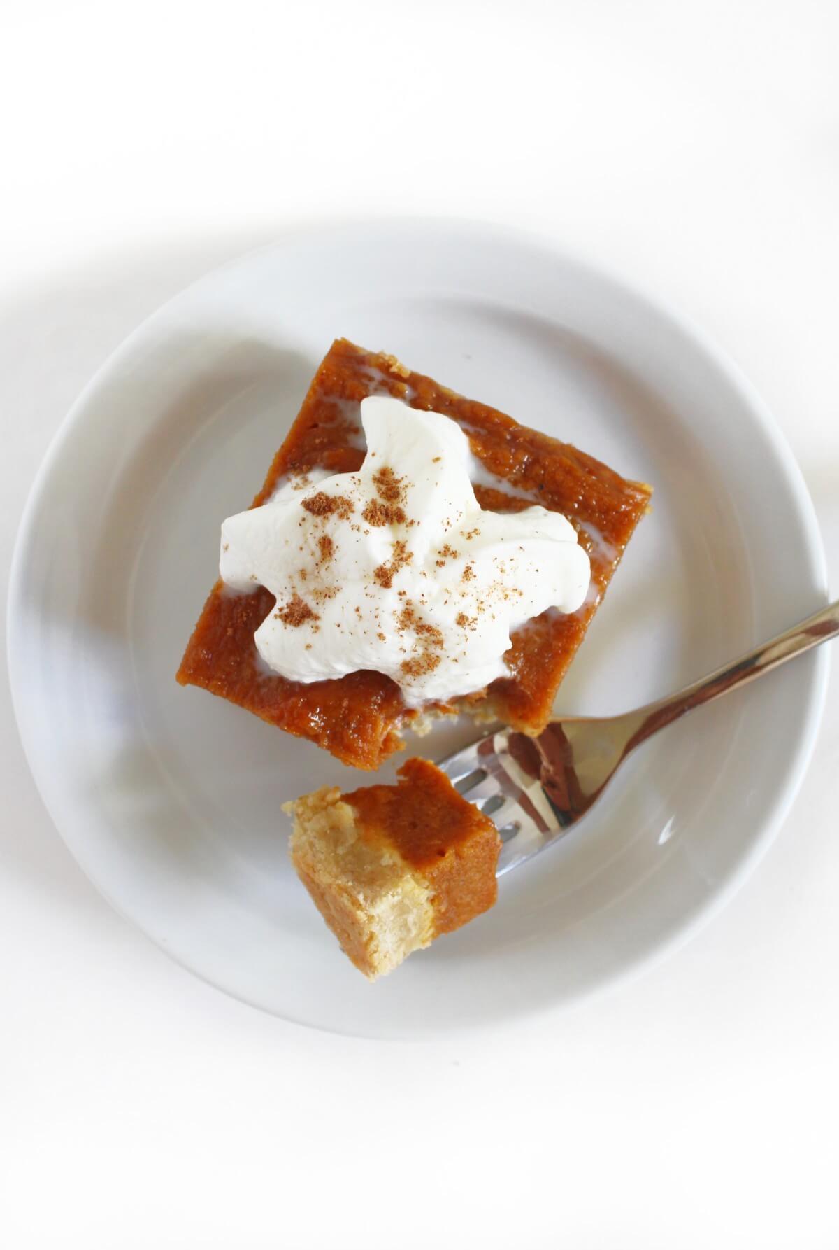 overhead view of vegan pumpkin pie bar with whipped cream topping.